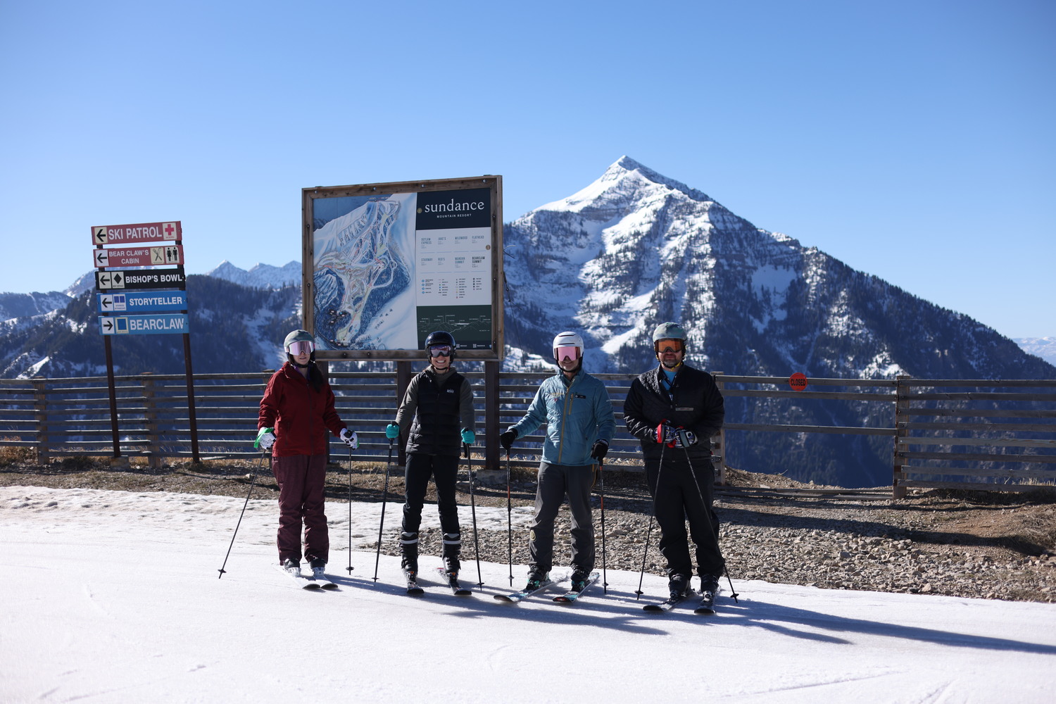four skiiers standing in front of sundance mountain resort sign